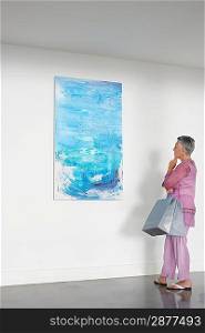 Woman observing painting in art gallery