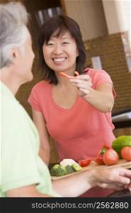 Woman Offering Husband A Piece Of Freshly Chopped Pepper