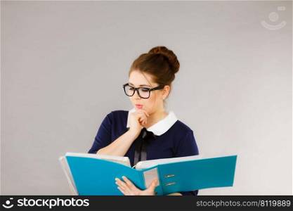 Woman office worker agent holding blue file folder in hands. Young elegant businesswoman or secretary with documents bills. Thinking face expression. Business and paperwork on grey. woman thinking holds file folder with documents