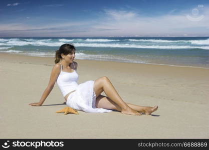 Woman on a beautiful beach with a starfish on the sand