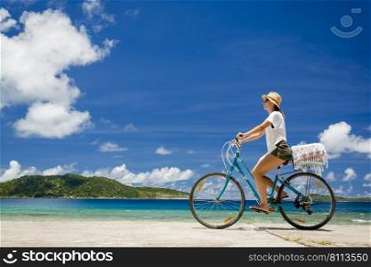 Woman on a bicycle ride along The Beach at Seychelles