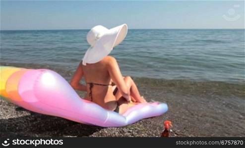 woman on a Pool Raft applying sunblock on the beach