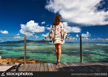 Woman on a tropical beach jetty at at Seychelles, La Digue.