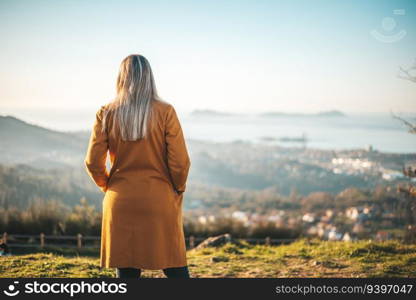 Woman on a yellow coat contemplating the landscape of Vigo, Galicia