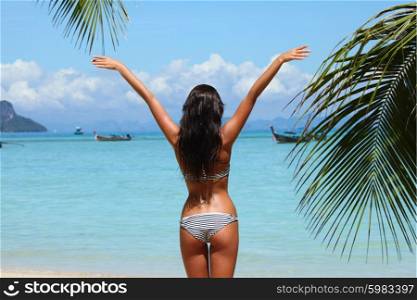 Woman on beach. Beautiful young woman standing on tropical beach with raised hands