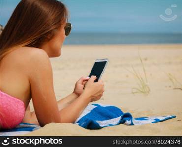 Woman on beach texting on smartphone.. Communication concept. Young woman spending time on summer beach texting messages on smartphone. Girl using mobile phone.