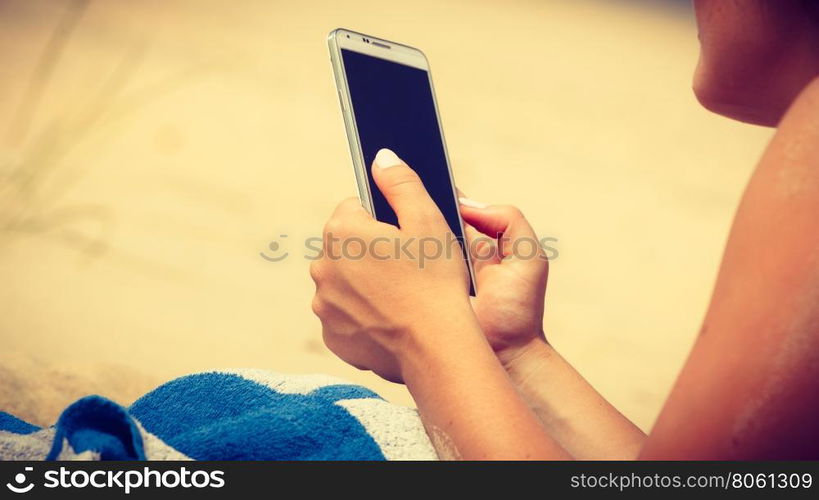 Woman on beach texting on smartphone.. Communication concept. Young woman spending time on summer beach texting messages on smartphone. Girl using mobile phone.