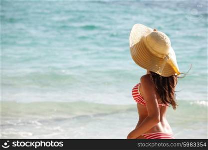 Woman on beach . Woman in sunhat and bikini standing on ocean beach on hot summer day