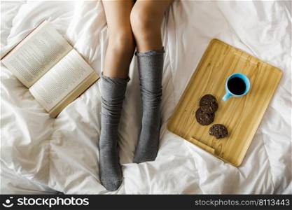 Woman on bed drinking a coffee with cookies