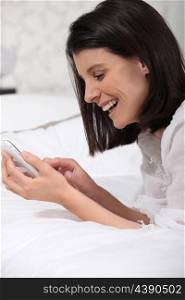 woman on bed laughing and watching a mobile phone