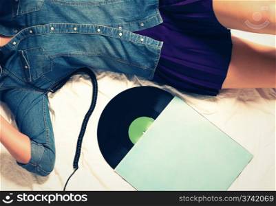 woman on bed with a vinyl record. body of woman wearing jeans button down and a skirt on bed with a vinyl record