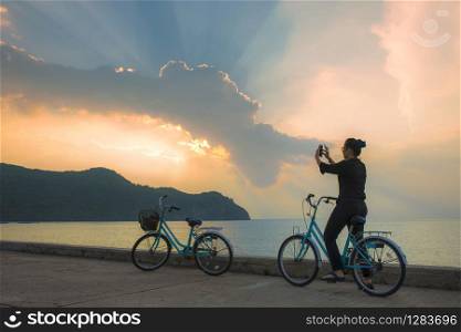 woman on bicycle taking photography by smart phone