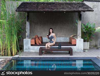 woman on chair and holding a glass in swimming pool. woman resting on chair and holding a glass in swimming pool