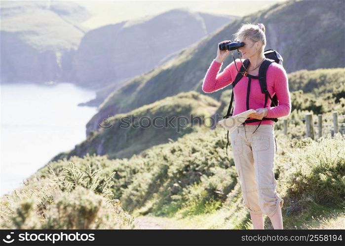 Woman on cliffside path using binoculars