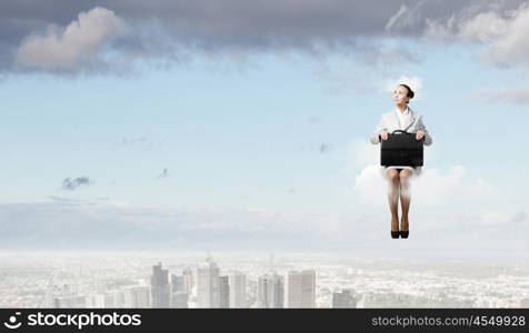 Woman on cloud. Young pretty businesswoman sitting on cloud high above city