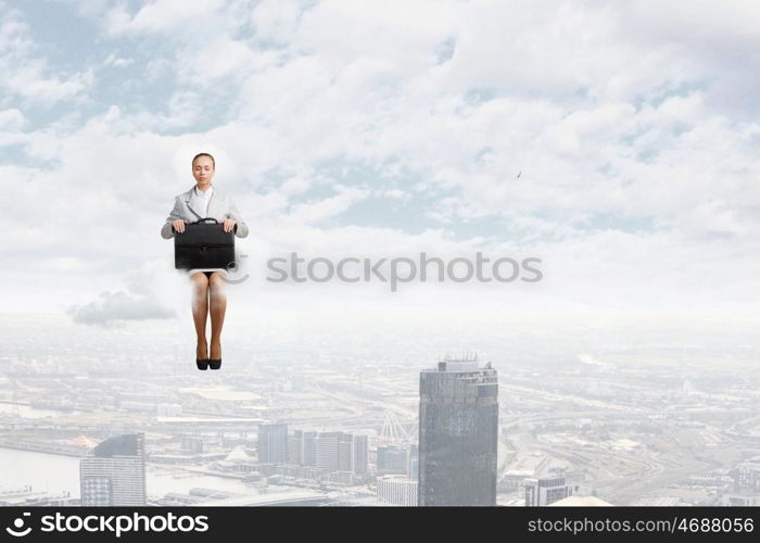 Woman on cloud. Young pretty businesswoman sitting on cloud high above city