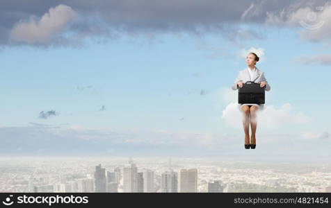 Woman on cloud. Young pretty businesswoman sitting on cloud high above city