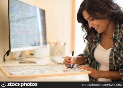Woman on computer desk wrinting on calendar
