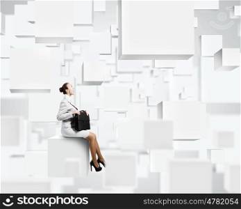 Woman on cube. Young pretty lady with suitcase sitting on white cube