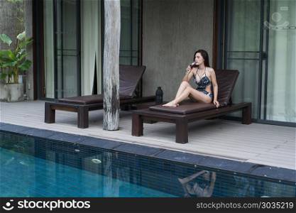 woman on deckchair and holding a glass in swimming pool