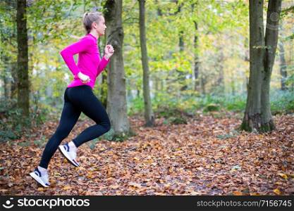 Woman On Early Morning Autumn Run Through Woodland Keeping Fit Through Exercise