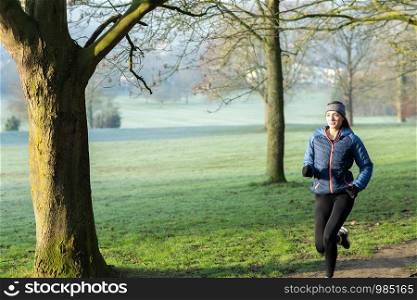 Woman On Early Morning Winter Run Through Park Keeping Fit Through Exercise