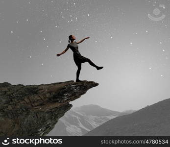 Woman on edge. Young woman walking at mountain edge at night