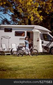 Woman on electric bike resting at the campsite. Family vacation travel, holiday trip in motorhome, Caravan car Vacation.
