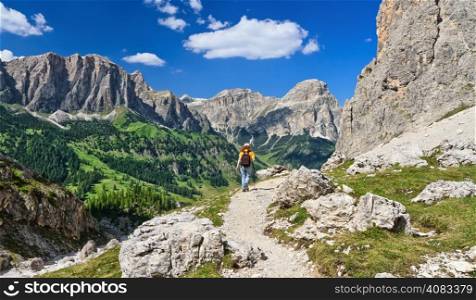 woman on footpath in Sella mountain, on background Colfosco and Badia Valley, south Tyrol, Italy
