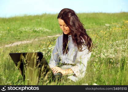 woman on green field work on laptop