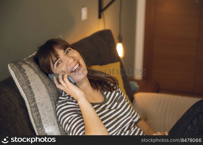 Woman on her bedroom, having a great chat at phone