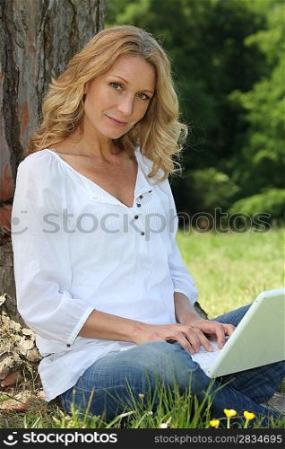Woman on laptop under tree