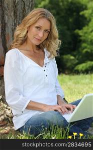 Woman on laptop under tree
