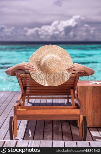 Woman on luxury beach resort, female tanning on sunbed, female wearing a big stylish hat, young girl enjoying beautiful seascape, relaxation on summer travel, tourism concept