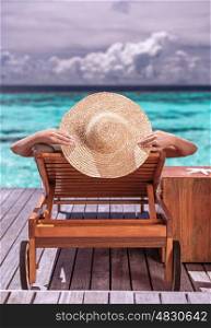 Woman on luxury beach resort, female tanning on sunbed, female wearing a big stylish hat, young girl enjoying beautiful seascape, relaxation on summer travel, tourism concept