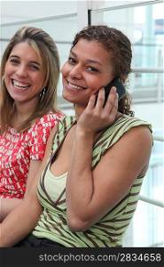Woman on mobile telephone sat next to friend