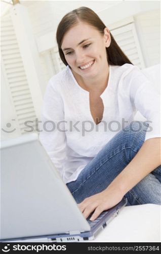 Woman on patio using laptop and smiling