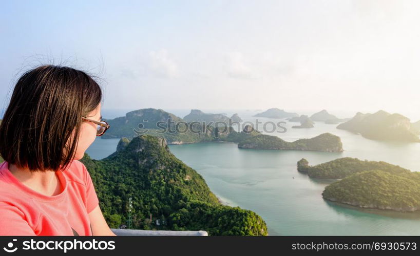 Woman on peak looking beautiful nature. Woman tourist on peak view point of Ko Wua Ta Lap island looking beautiful nature landscape during sunrise over the sea in Mu Ko Ang Thong National Park, Surat Thani, Thailand, 16:9 widescreen