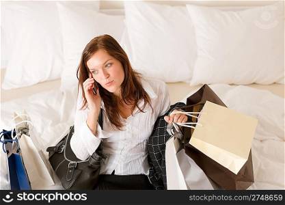 Woman on phone - back home from shopping sitting on bed