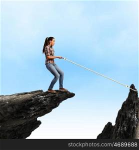 Woman on rock. Young woman in casual catching rock with rope