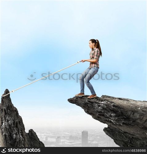 Woman on rock. Young woman in casual catching rock with rope