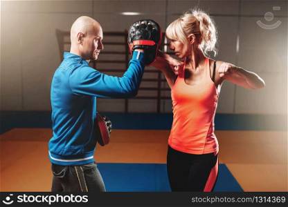 Woman on self defense training with male trainer, fighting workout in gym, martial art. Woman on self defense training with male trainer