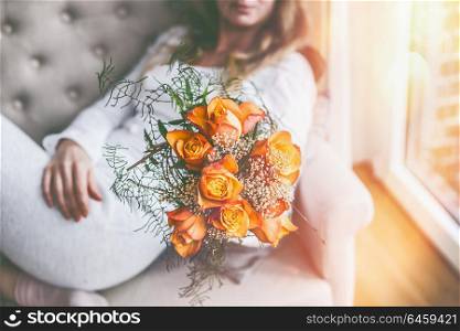 Woman on sofa at window with Roses bunch in hand
