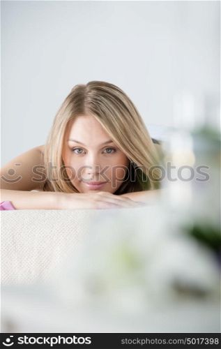Woman on spa or massage with flowers and cosmetics on foreground making perfect copyspace
