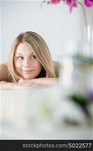 Woman on spa or massage with flowers and cosmetics on foreground making perfect copyspace