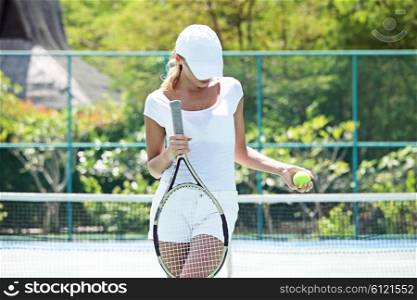 Woman on tennis court. Beautiful young woman on tennis court of tropical resort
