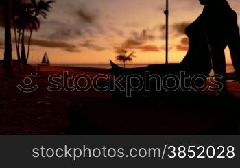 Woman on the beach and yacht sailing at sunset