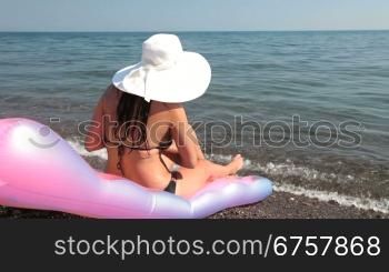 woman on the beach putting on lotion