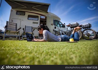 Woman on the grass, looking at the laptop near the ?amping. Caravan car Vacation. Family vacation travel, holiday trip in motorhome