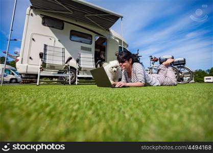 Woman on the grass with a dog looking at a laptop. Caravan car Vacation. Family vacation travel, holiday trip in motorhome